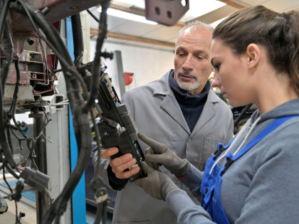 Image showing mentor helping a younger employee understand how to operate a machine..